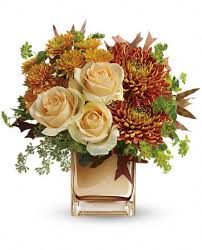 Cream roses and orange chrysanthemums in a clear vase