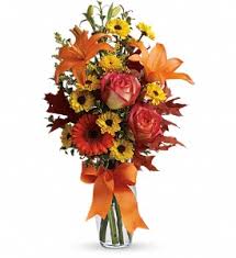 Bouquet of orange lilies, pink roses, and yellow daisies in a glass vase