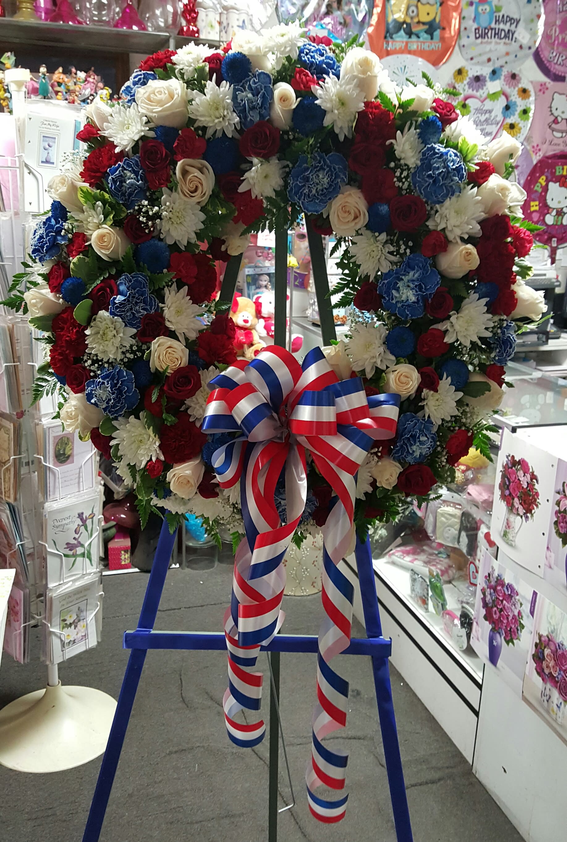 Large floral wreath with red, white, and blue flowers on an easel
