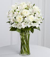 White roses and white orchids in a clear glass vase