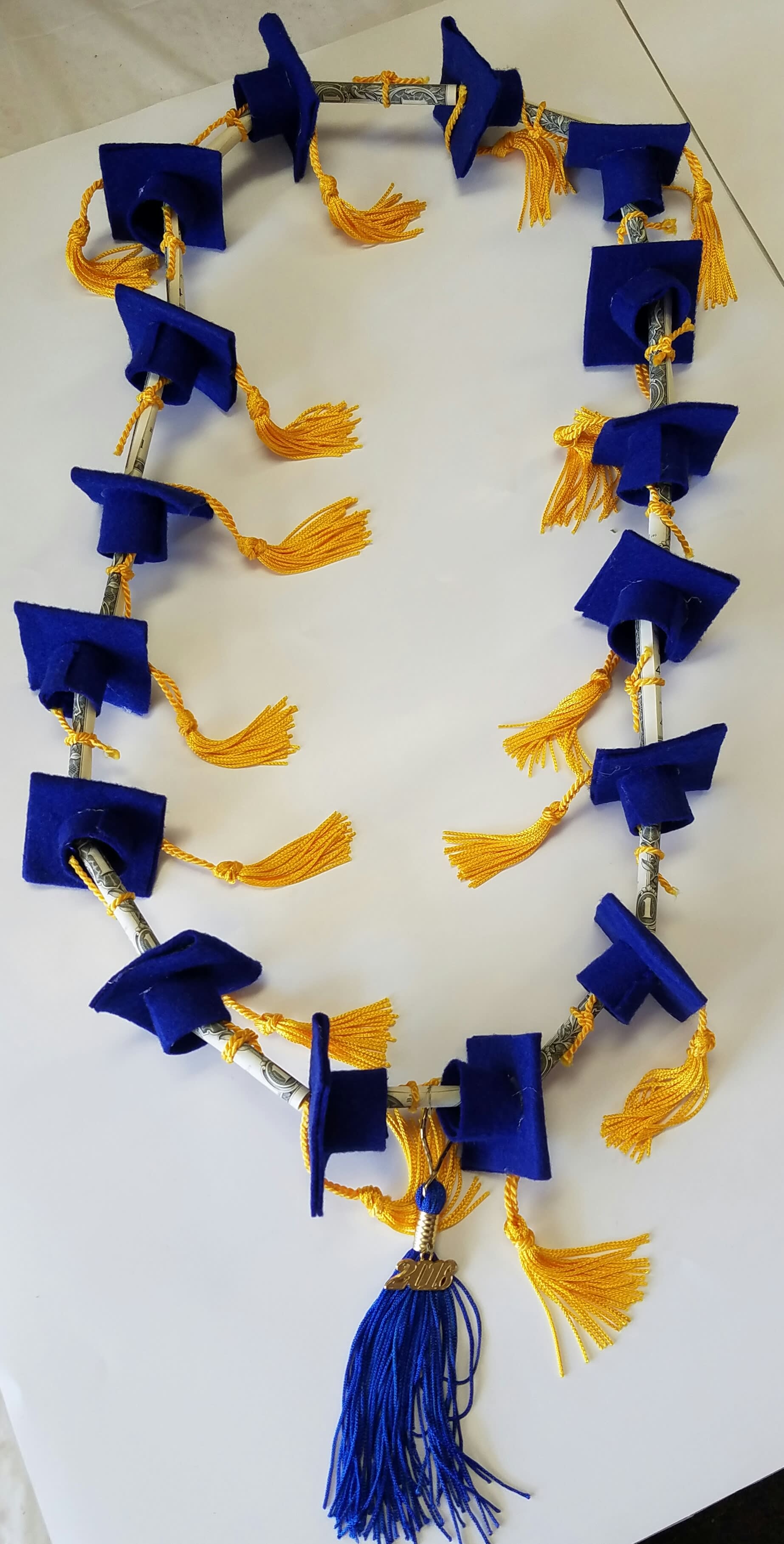 Blue and gold graduation lei made from folded bills and tassels