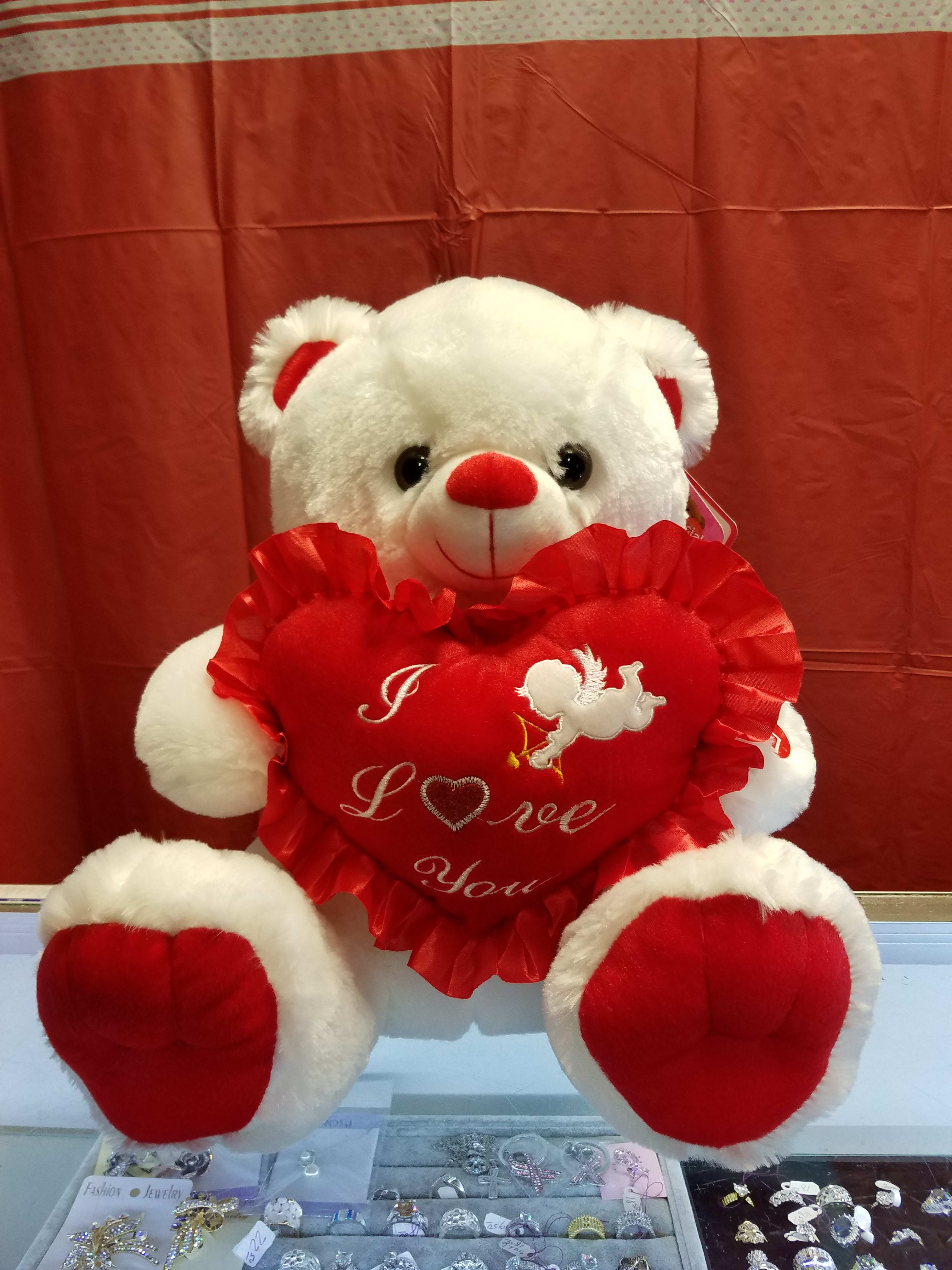 White teddy bear holding a red heart pillow with "I Love You" text