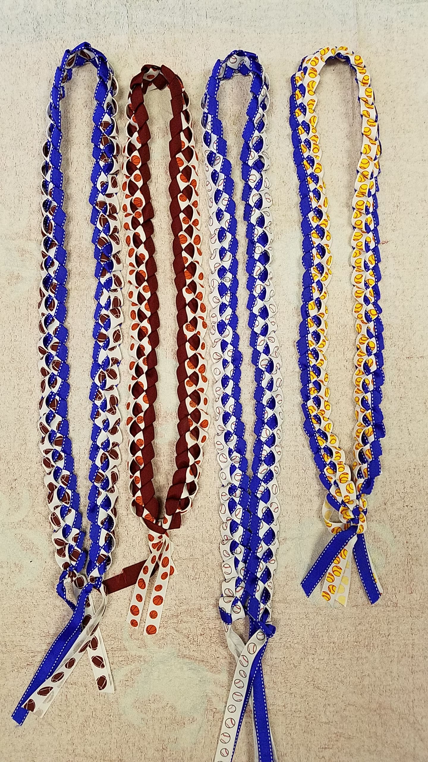 Braided ribbon leis in blue, maroon, white, and yellow with sports prints
