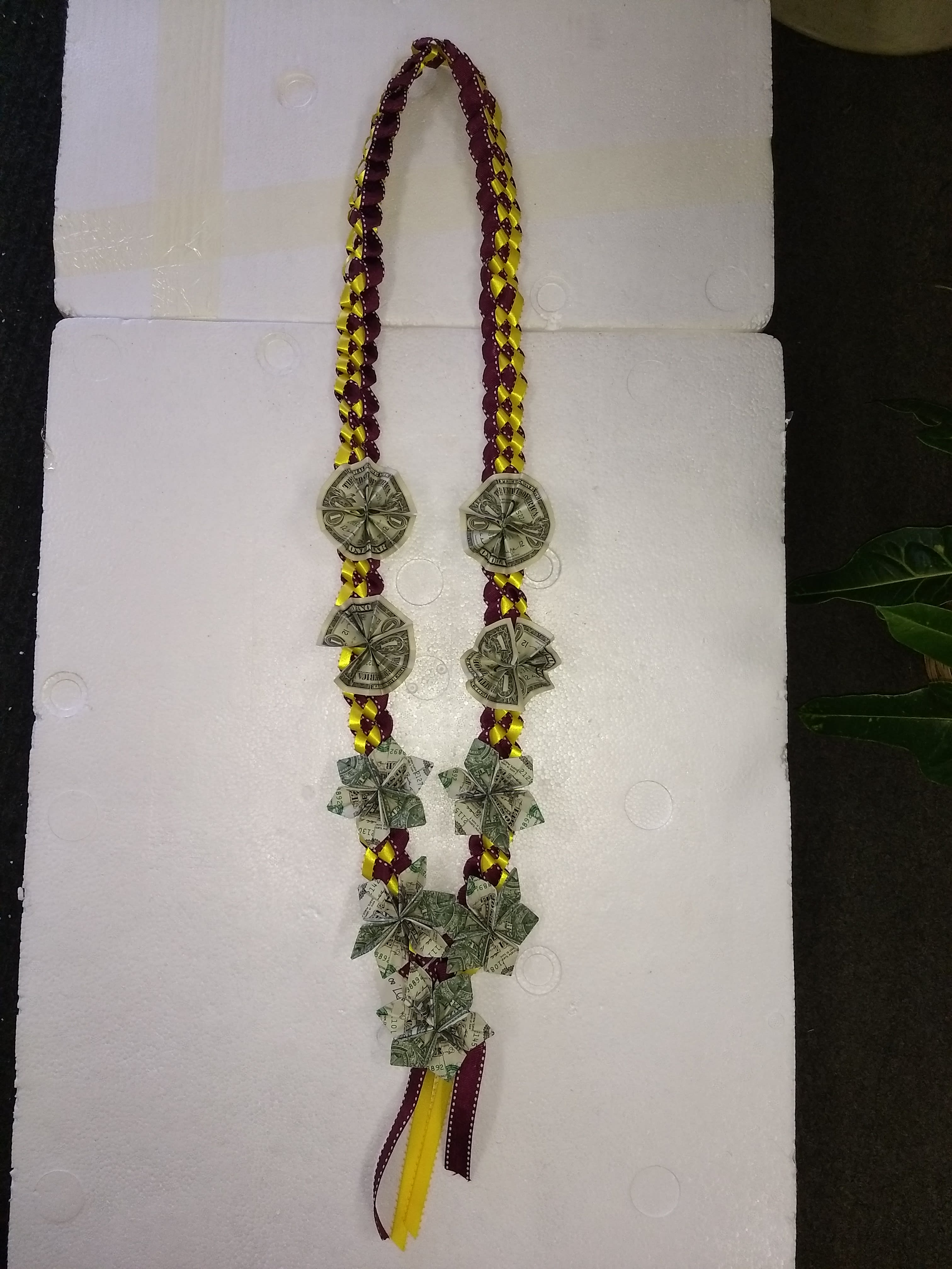 Braided ribbon lei with folded dollar bills