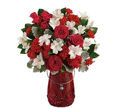 Red and white flower bouquet in a red vase with a heart charm