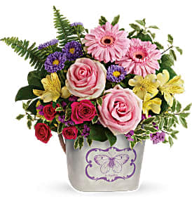 Mixed bouquet of pink roses, gerbera daisies, and purple flowers in a decorative vase