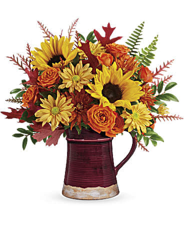 Sunflower and orange rose arrangement in a burgundy pitcher vase