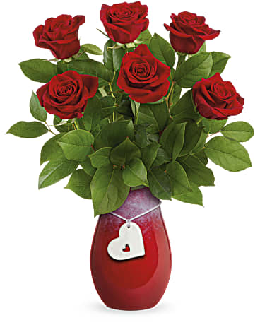 Red roses in a red vase with a white heart tag