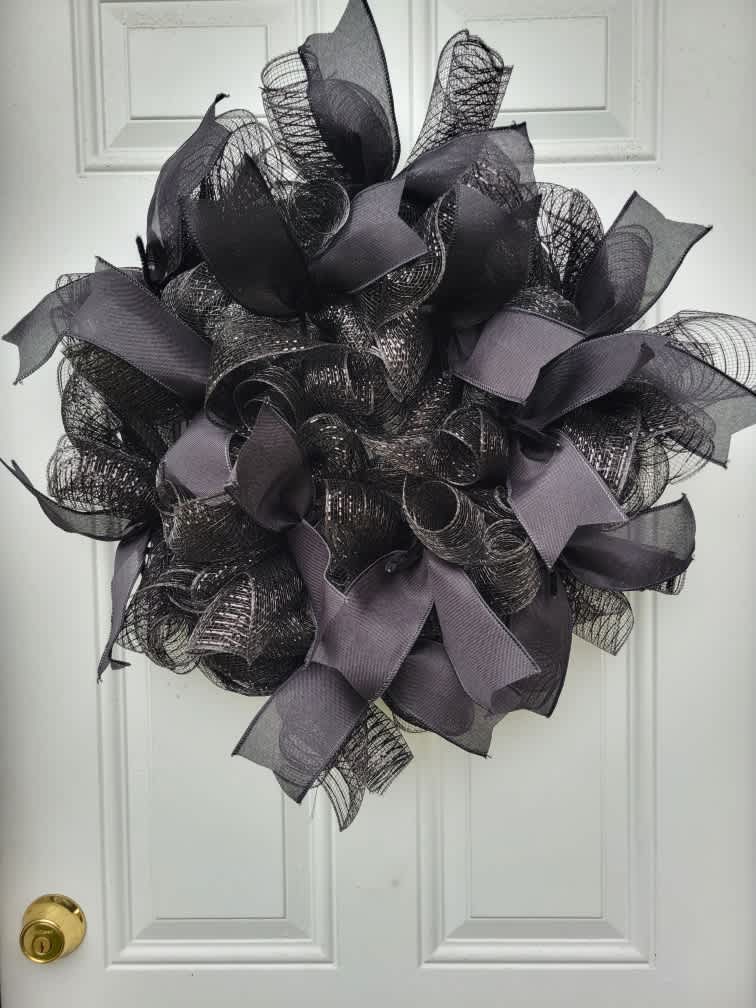 Black mesh wreath with gray ribbon loops on a white door