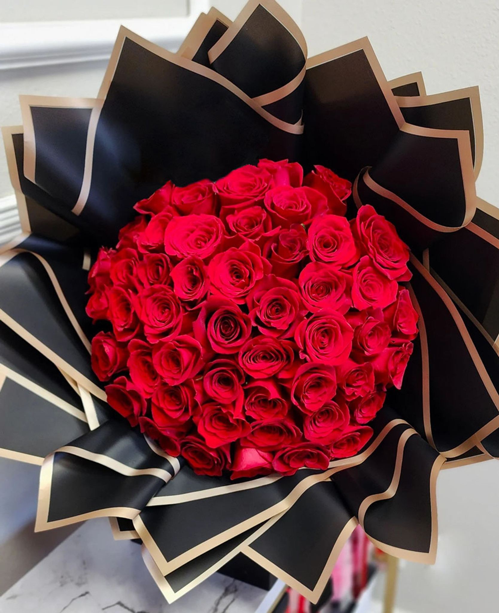 Bouquet of red roses wrapped in black paper with gold trim