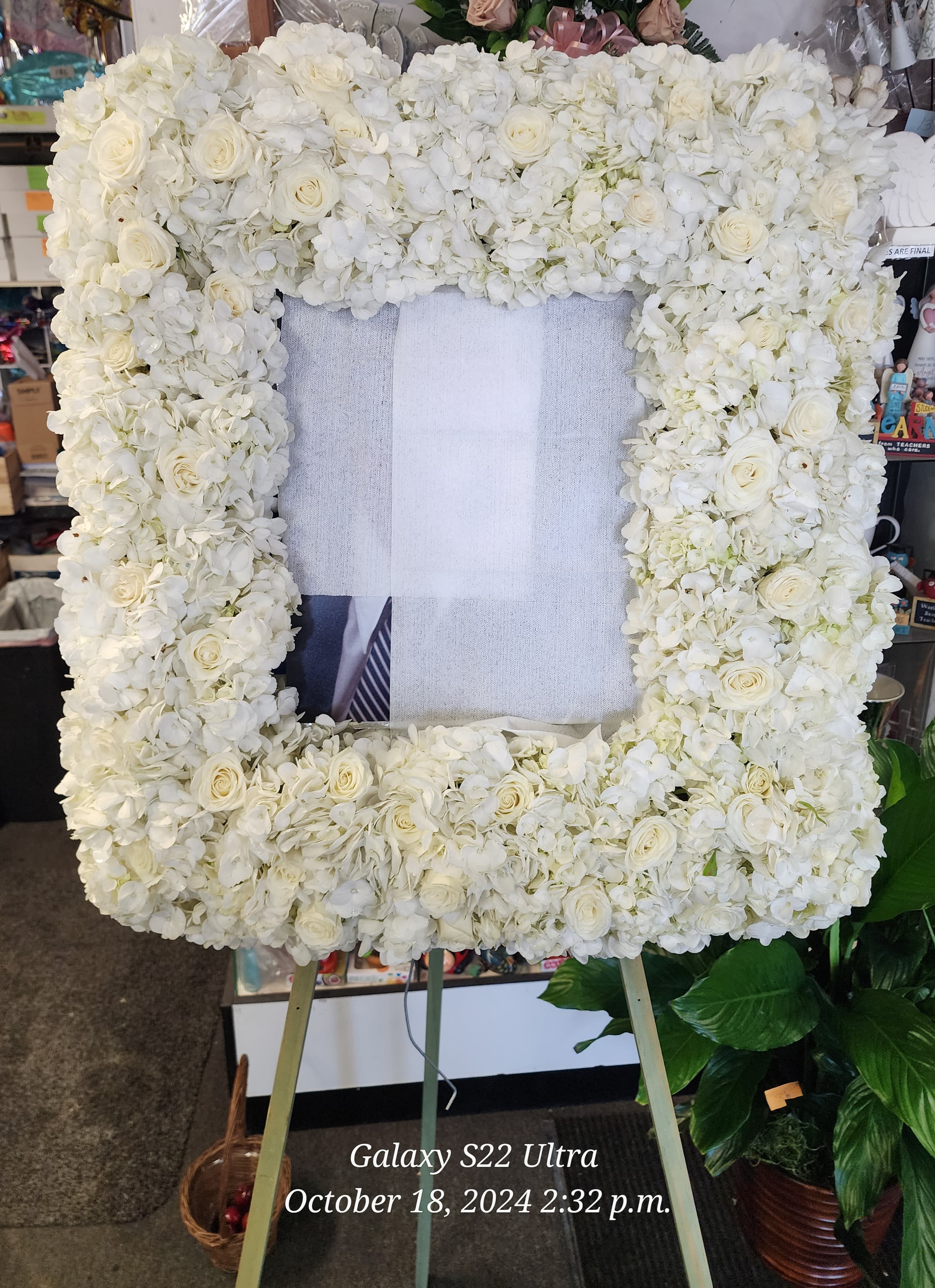 White floral standing frame with roses and hydrangeas on an easel