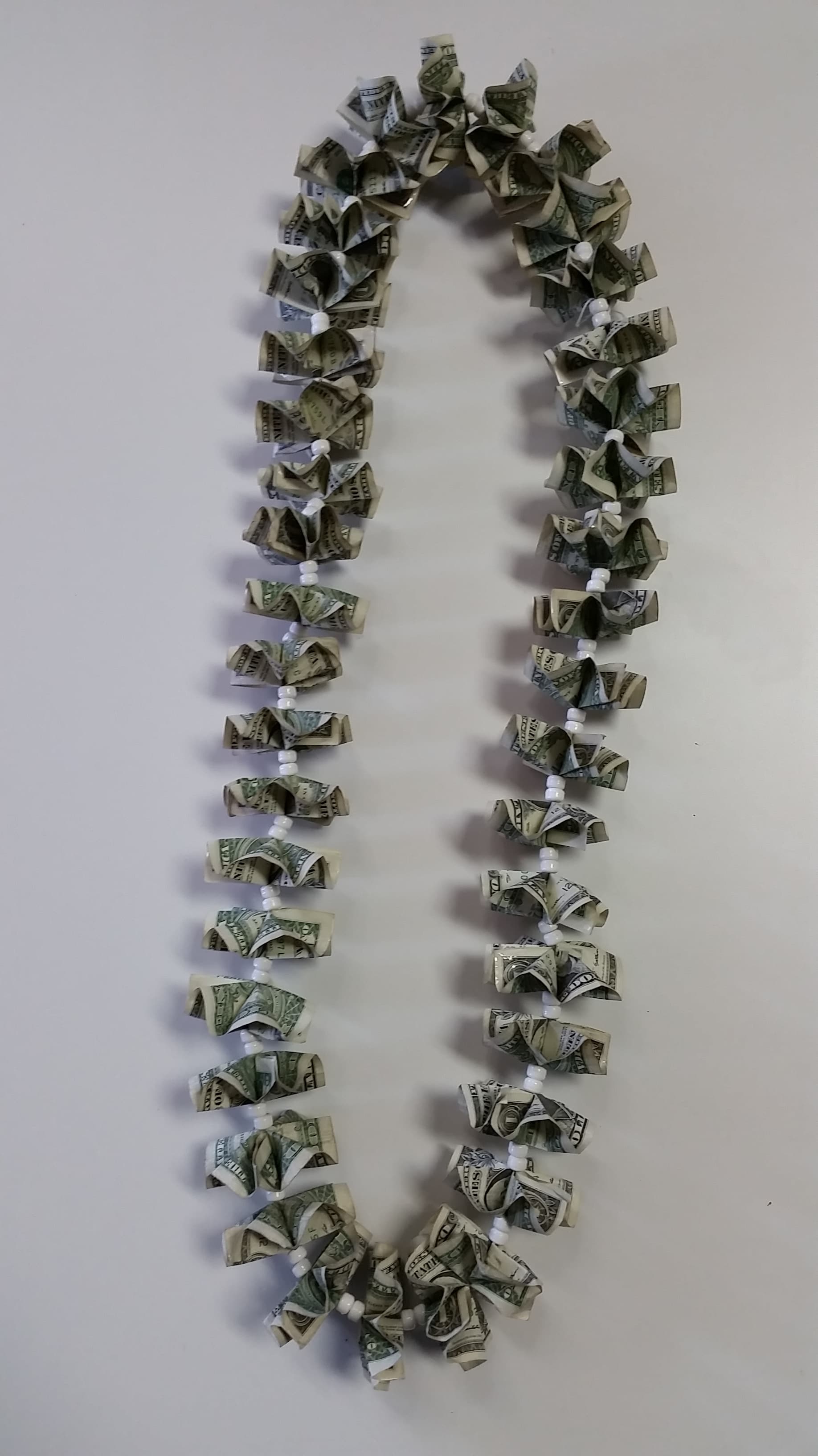 Money lei made from folded dollar bills and white beads