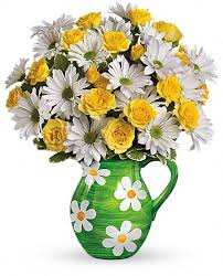 Yellow roses and white daisies in a green pitcher vase