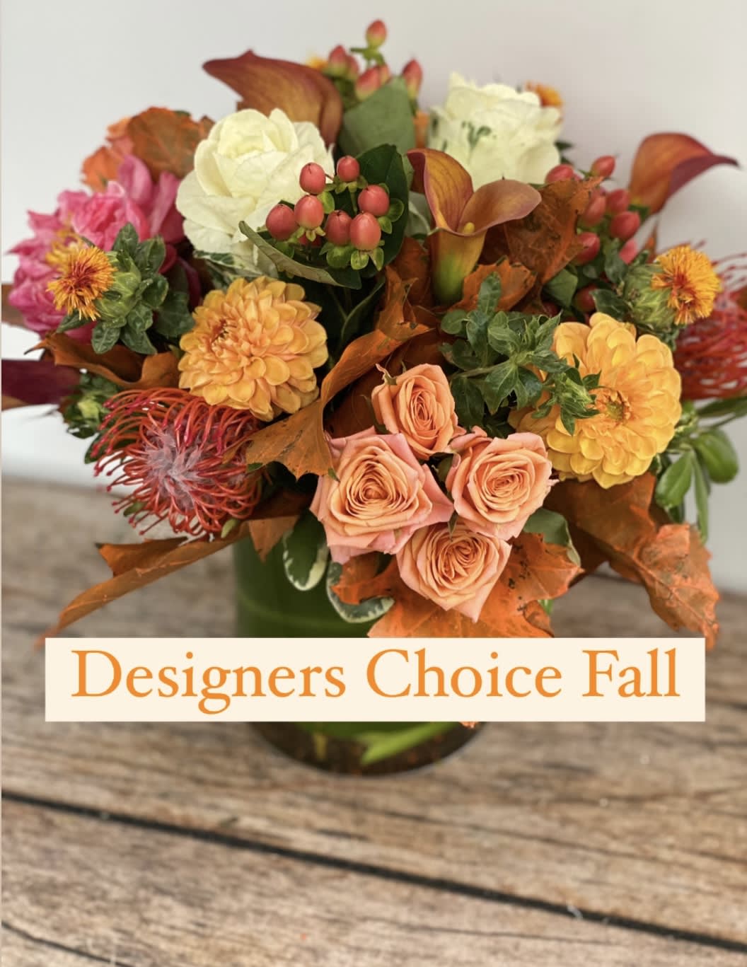 Fall bouquet with peach roses, yellow blooms, and orange foliage in a vase