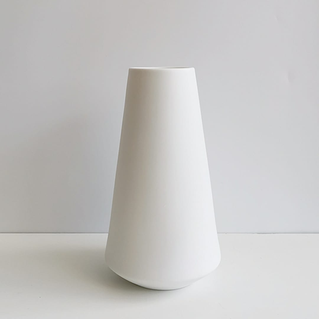 Tall white ceramic vase on a plain background