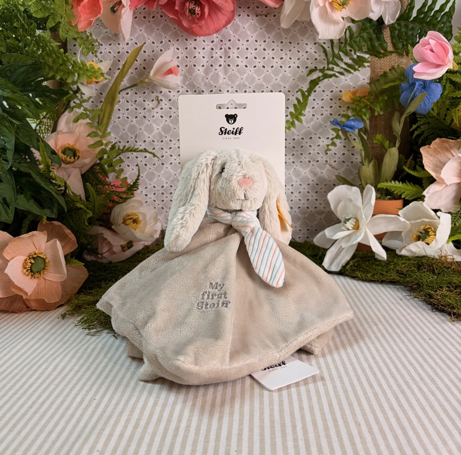 Hoppie Rabbit Security Blanket Baby Toy - This adorable Hoppie Rabbit security blanket measures 10 inches and is made of the softest plush. She has long ears, a round head with embroidered eyes, nose and mouth, and a little striped scarf.  Like all Steiff products, this Hoppie Rabbit proudly wears the world-famous a Button in ear trademark, the symbol of highest quality and safety.