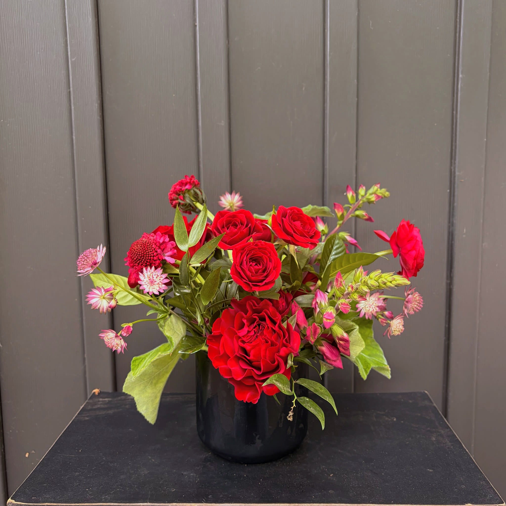 Wild Cherry - A bright cherry inspired arrangement in a black ceramic vessel. Upgrade to deluxe or premium for additional luxe blooms.
