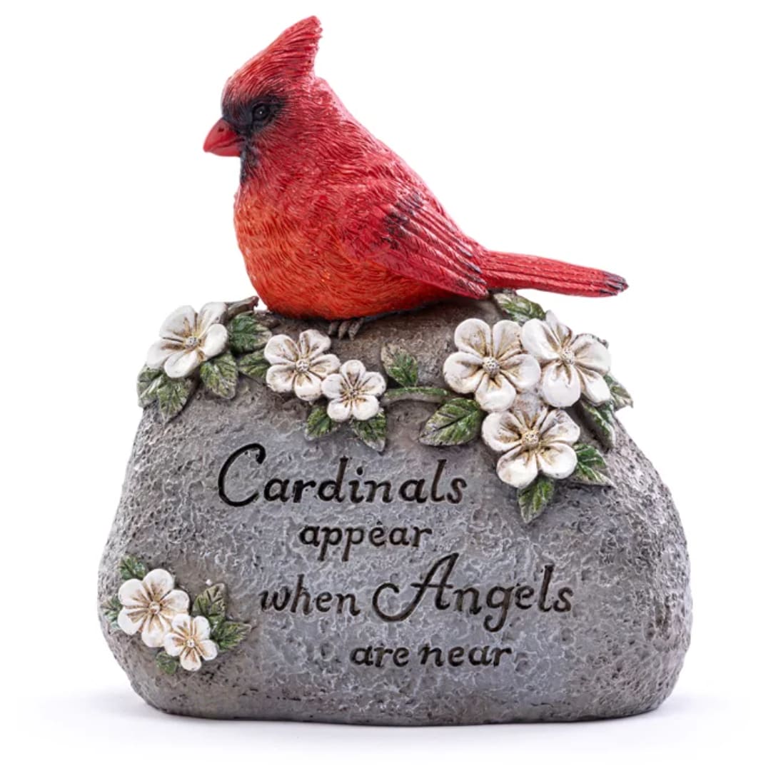 Red cardinal figurine on a gray memorial stone with white flowers