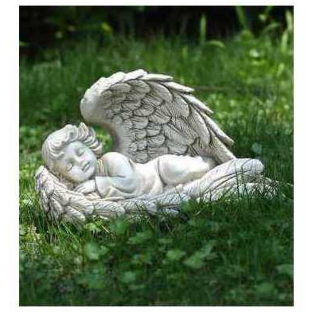 Stone angel statue lying in grass outdoors