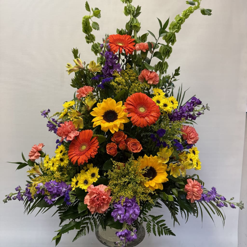 Tall mixed flower arrangement with sunflowers, gerbera daisies, and carnations in a vase