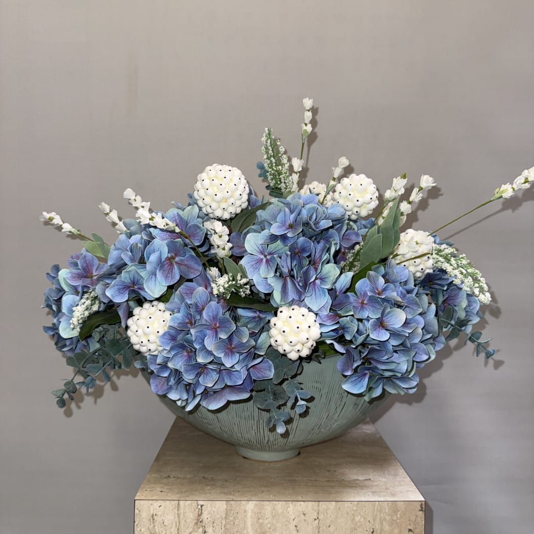 Blue hydrangea arrangement in a pale ceramic bowl with white accent flowers