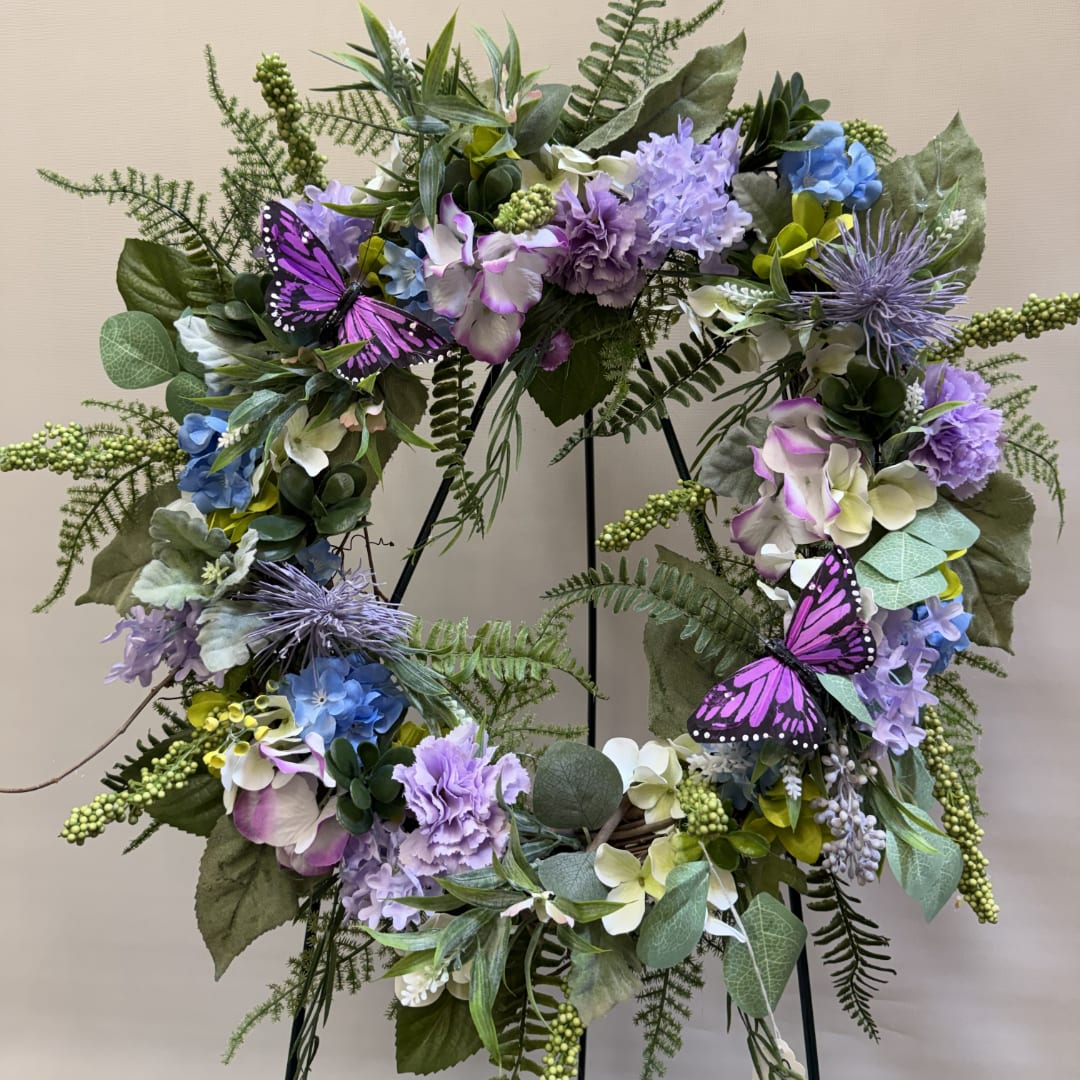 Purple and blue floral wreath with butterflies on a stand