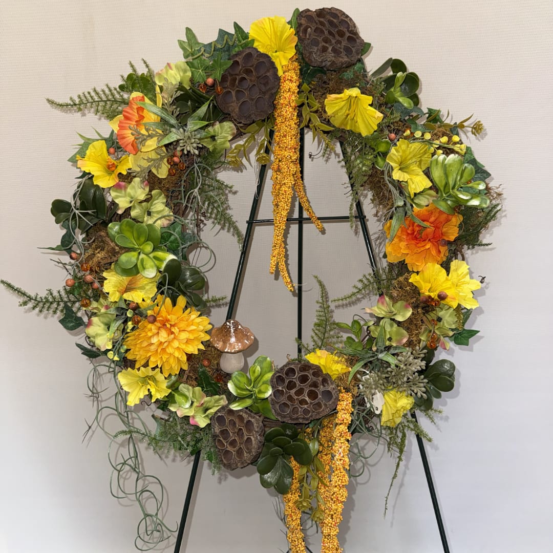 Large floral wreath with yellow and orange blooms on a stand