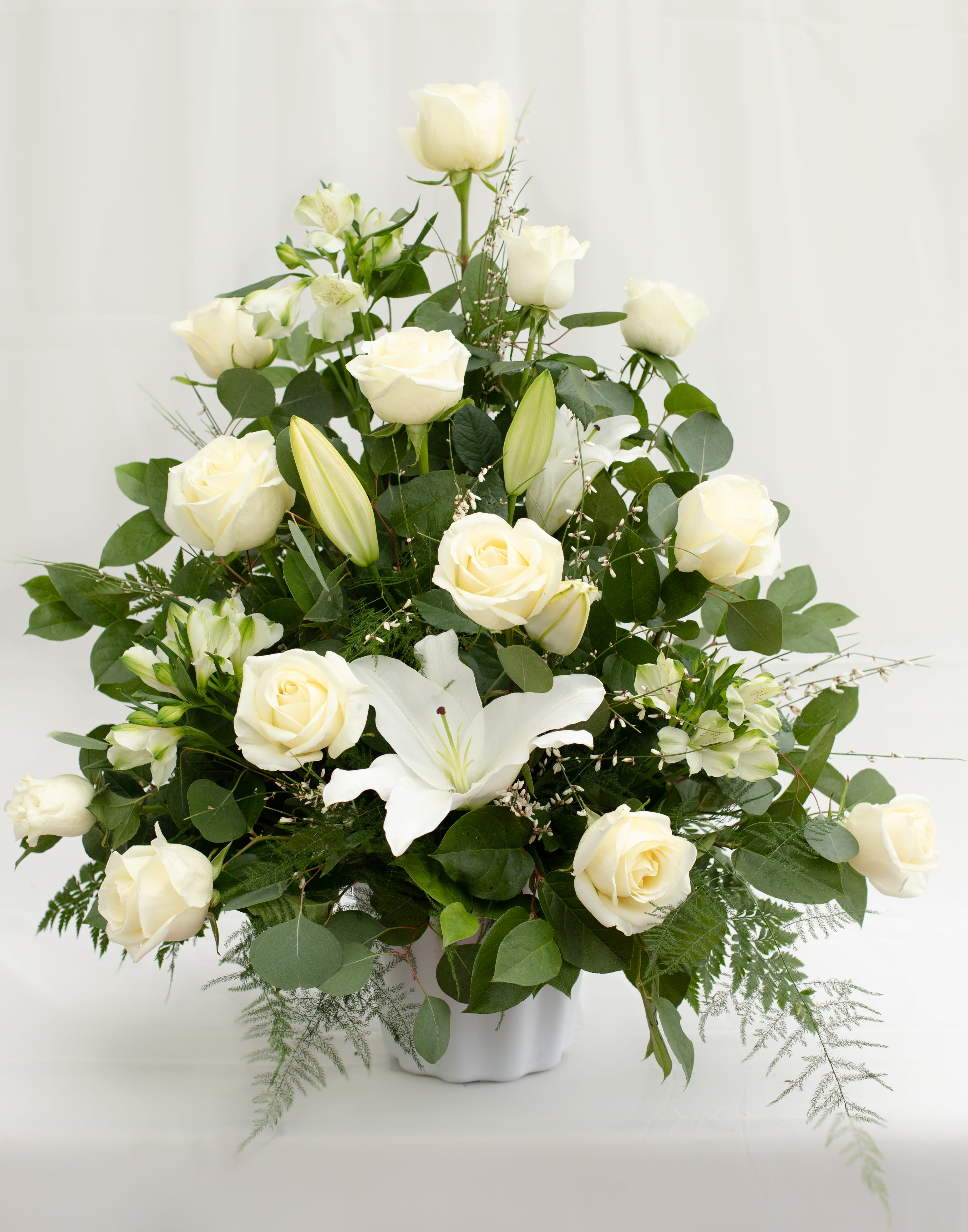 White roses and lilies arranged in a white vase