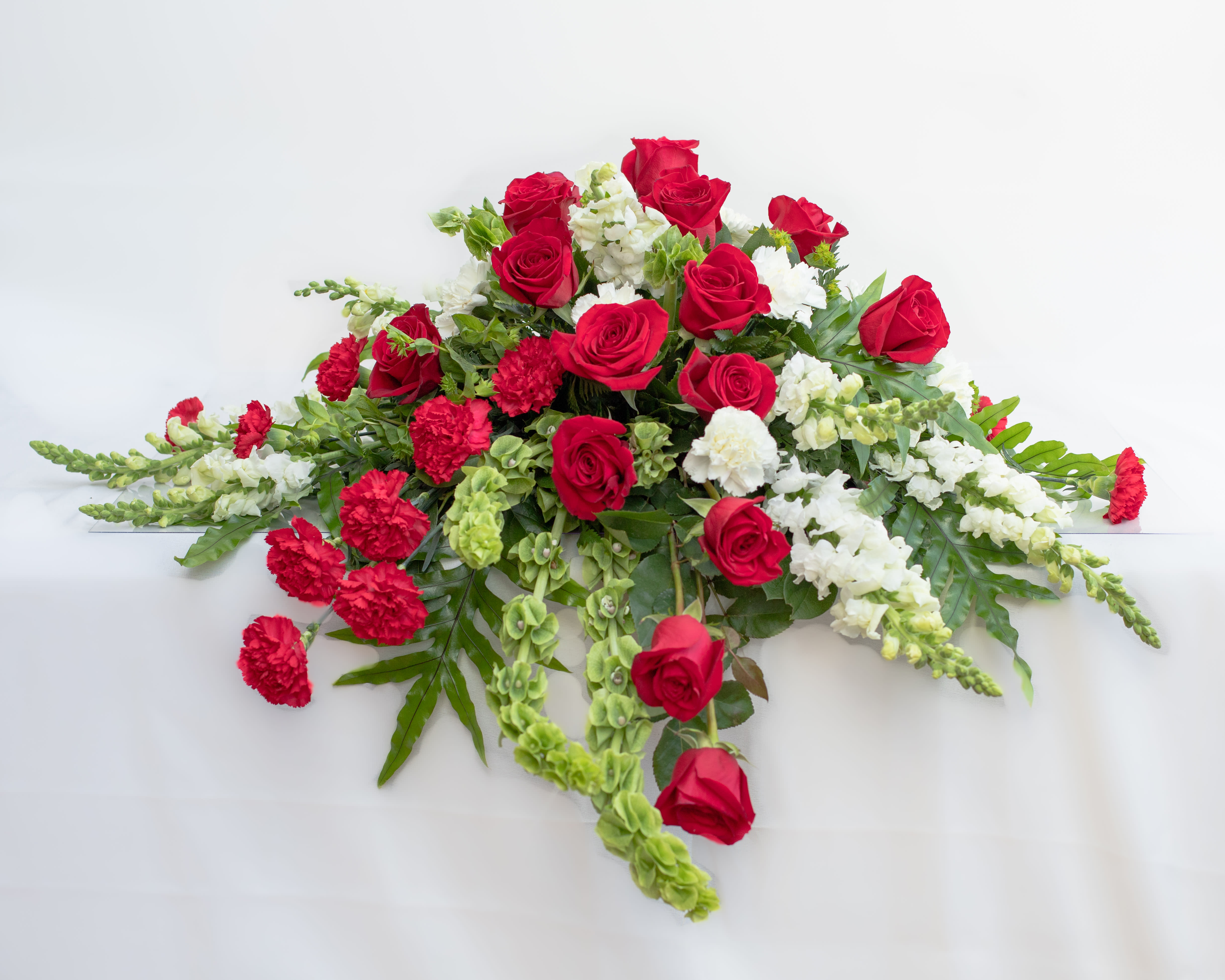 Red roses and white flowers arranged in a low spray