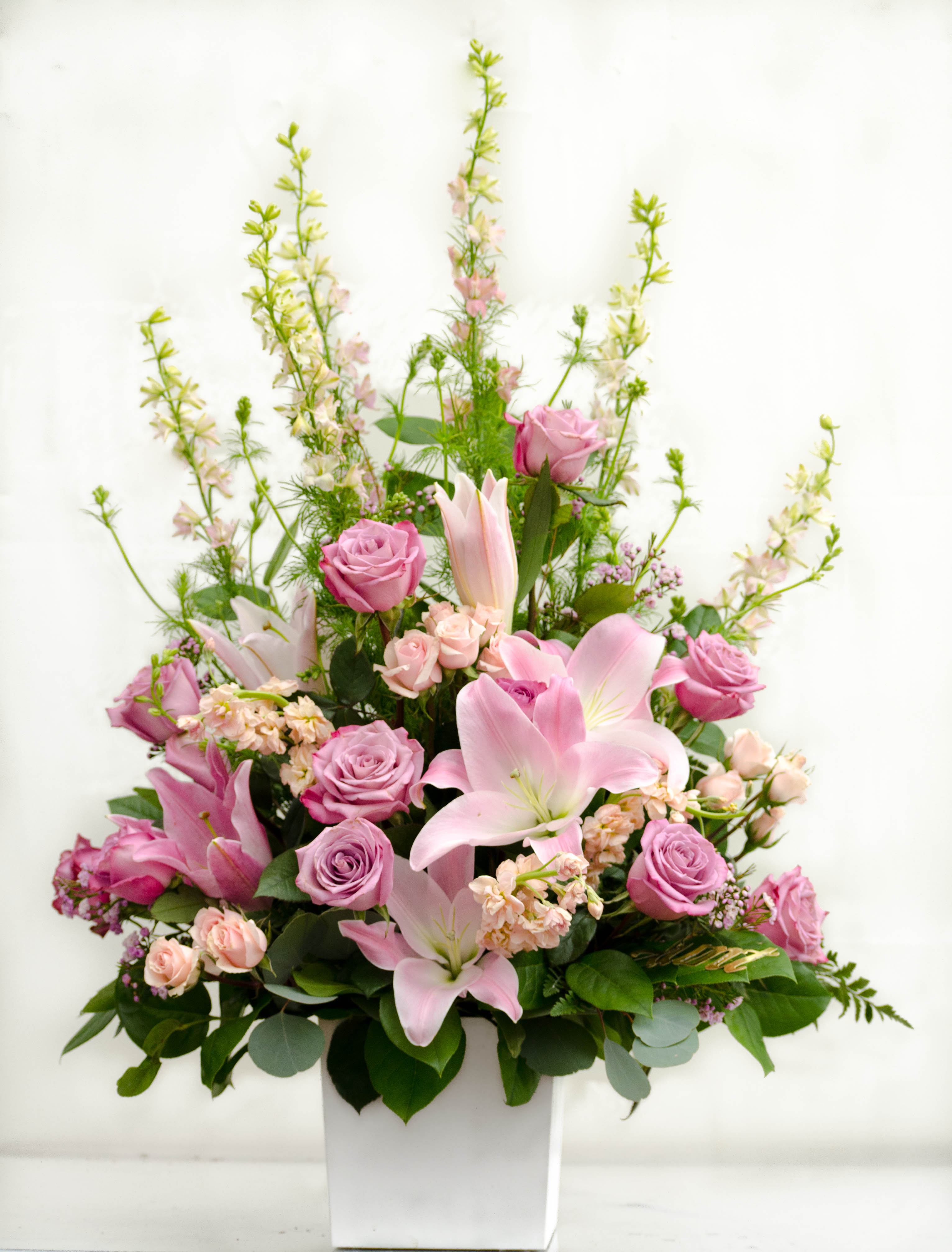 Pink roses and lilies arranged in a white vase