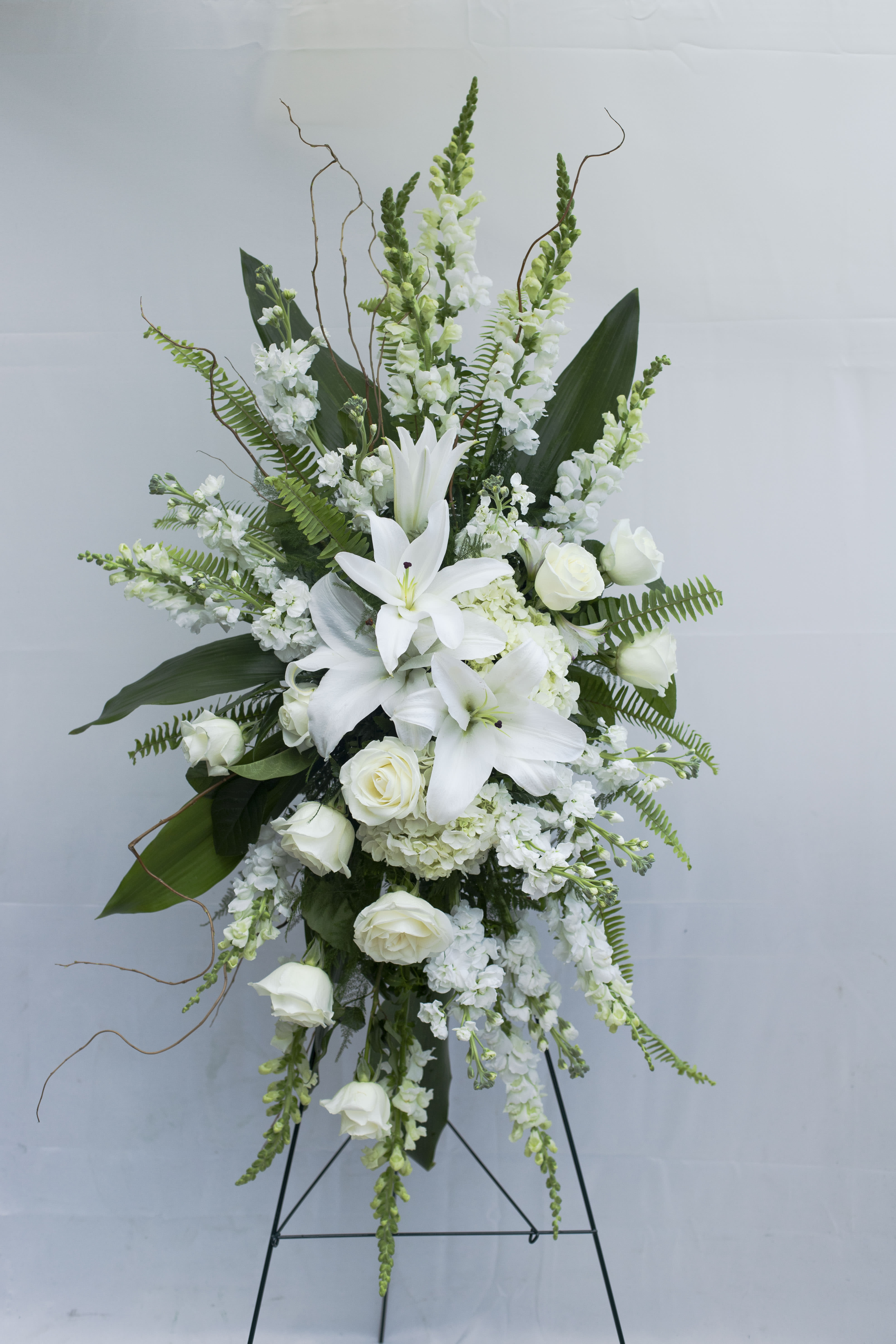 White lilies and roses in a tall standing floral arrangement