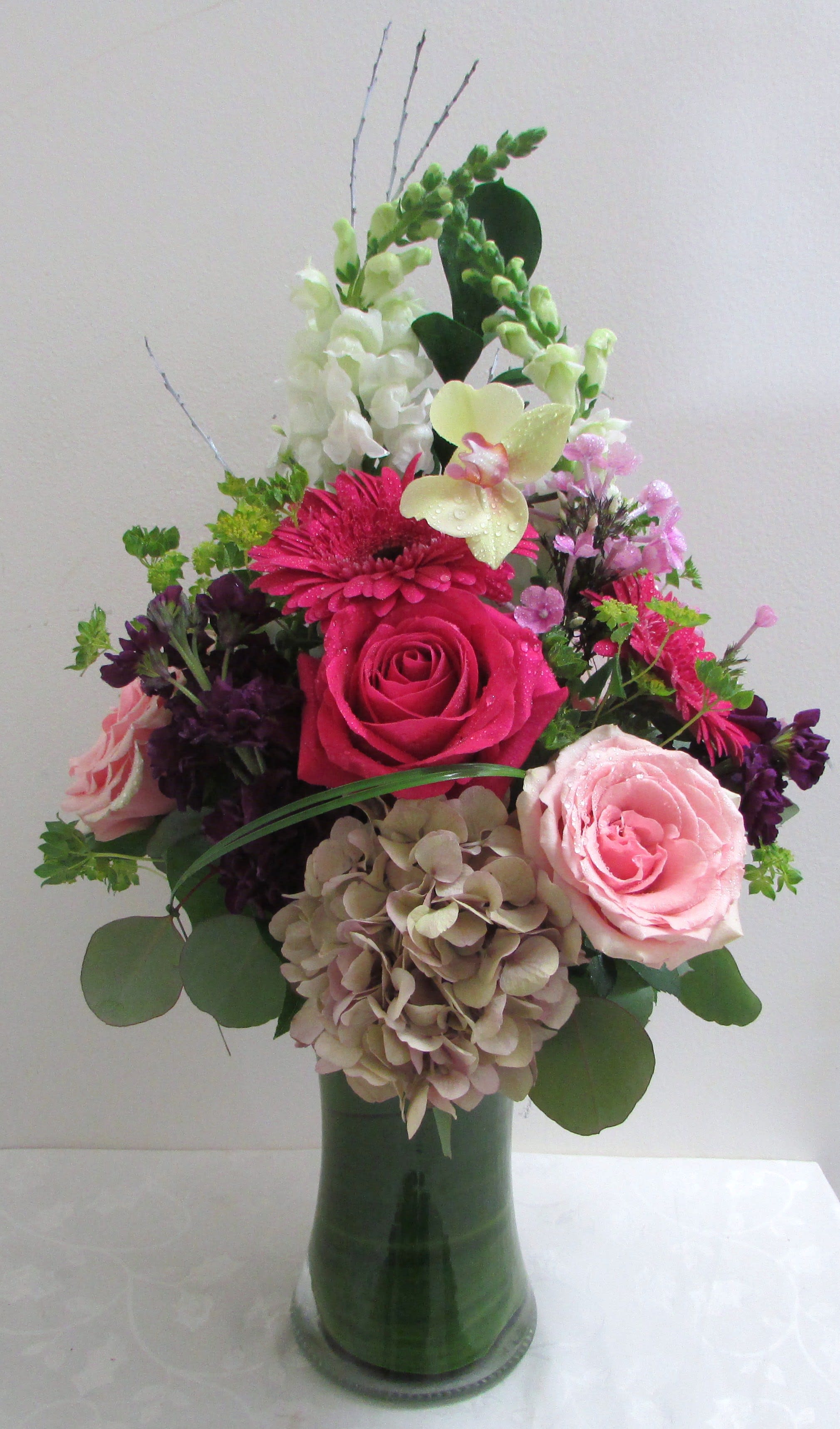 Mixed pink and white flowers arranged in a tall glass vase