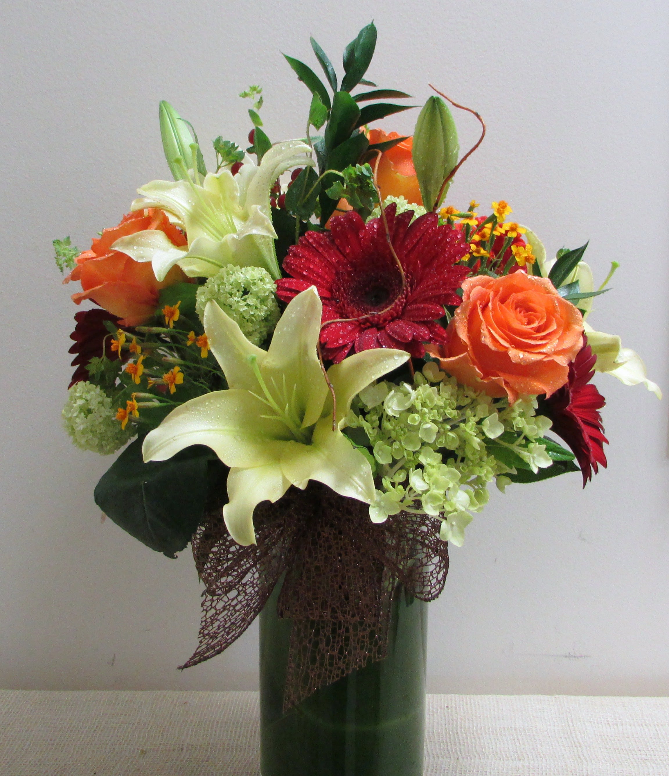 F4 - A mix of Fall colored mixed flowers arranged in a glass vase