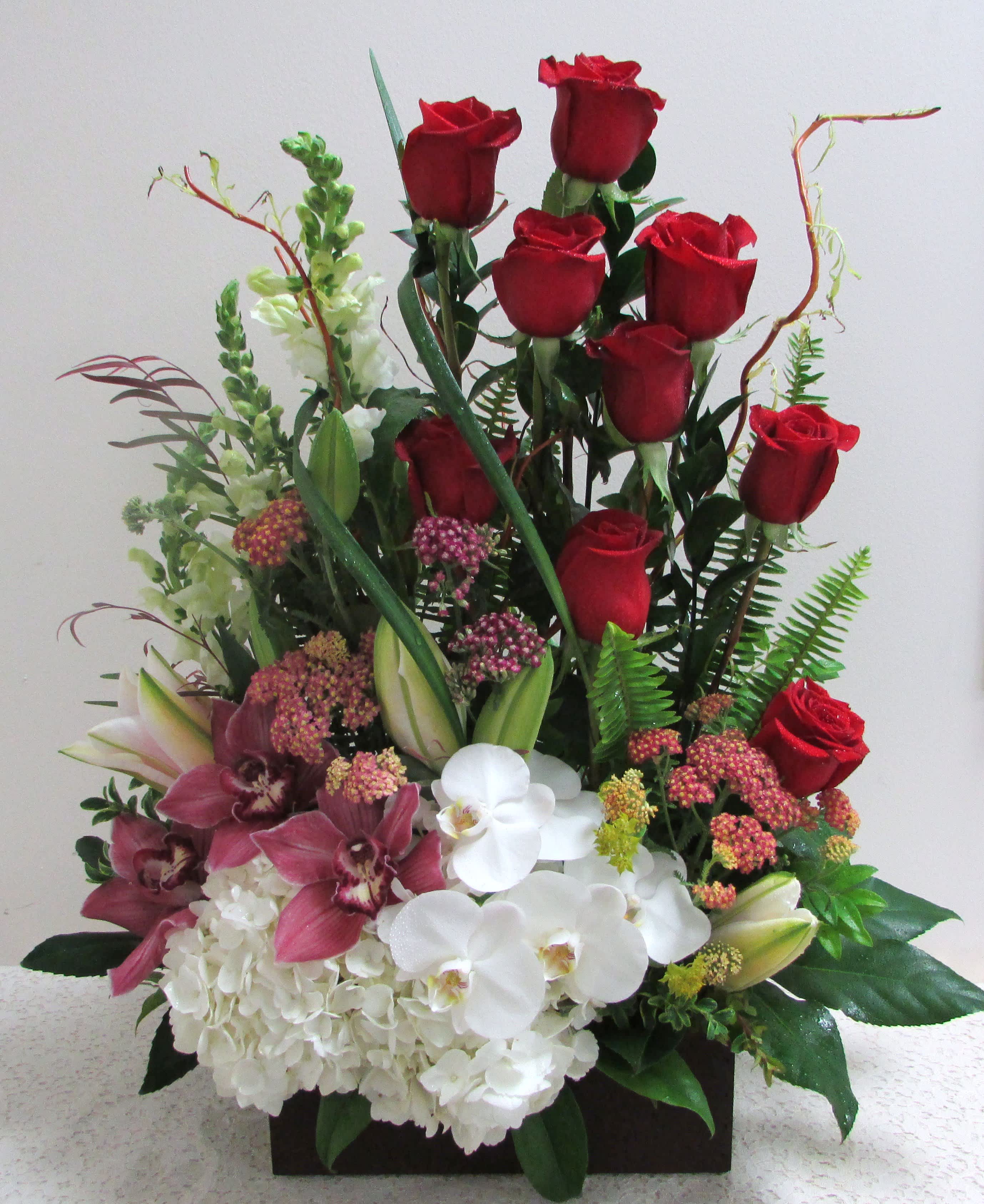 Red roses with white orchids and pink flowers in a rectangular container