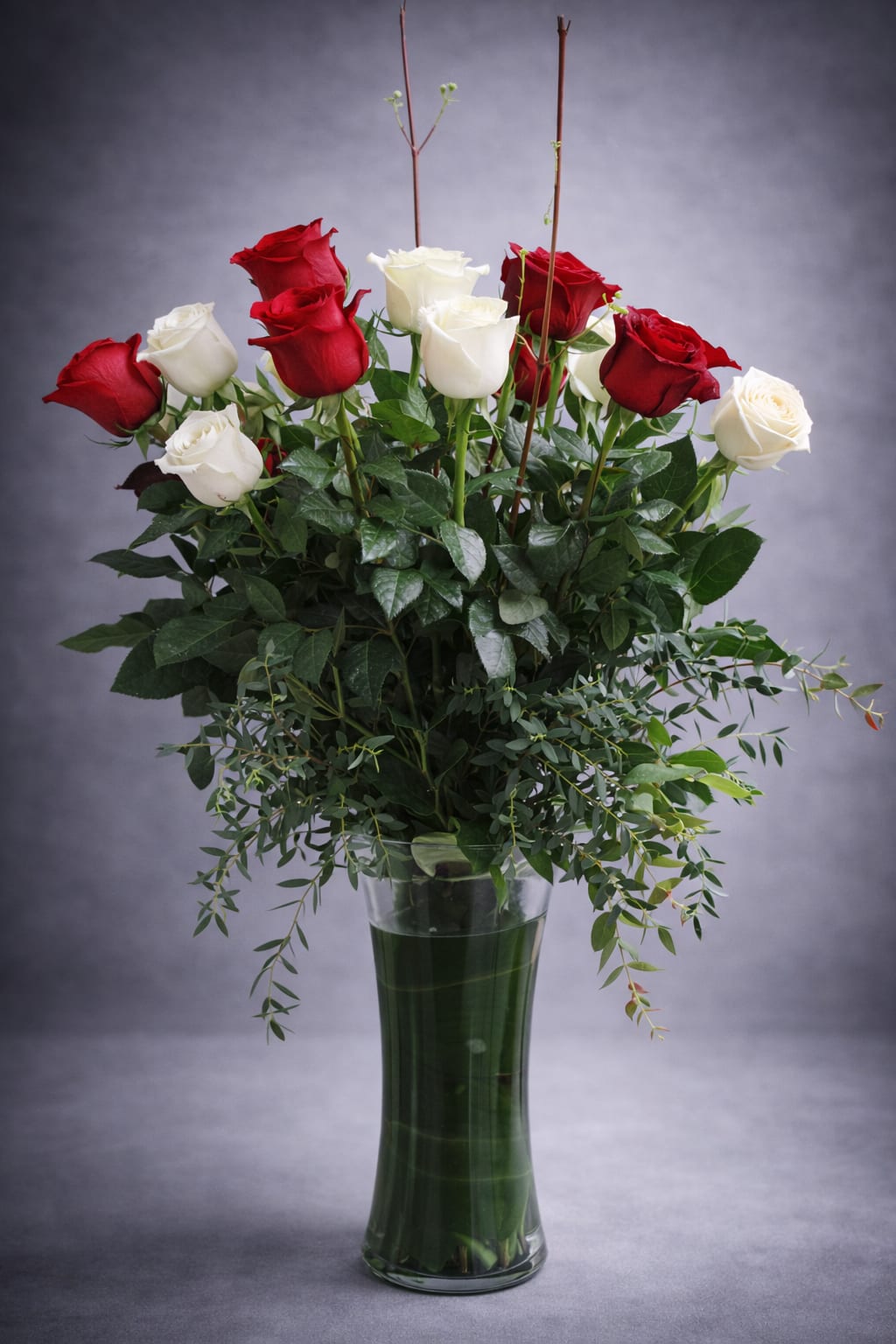 Red and white roses in a tall glass vase