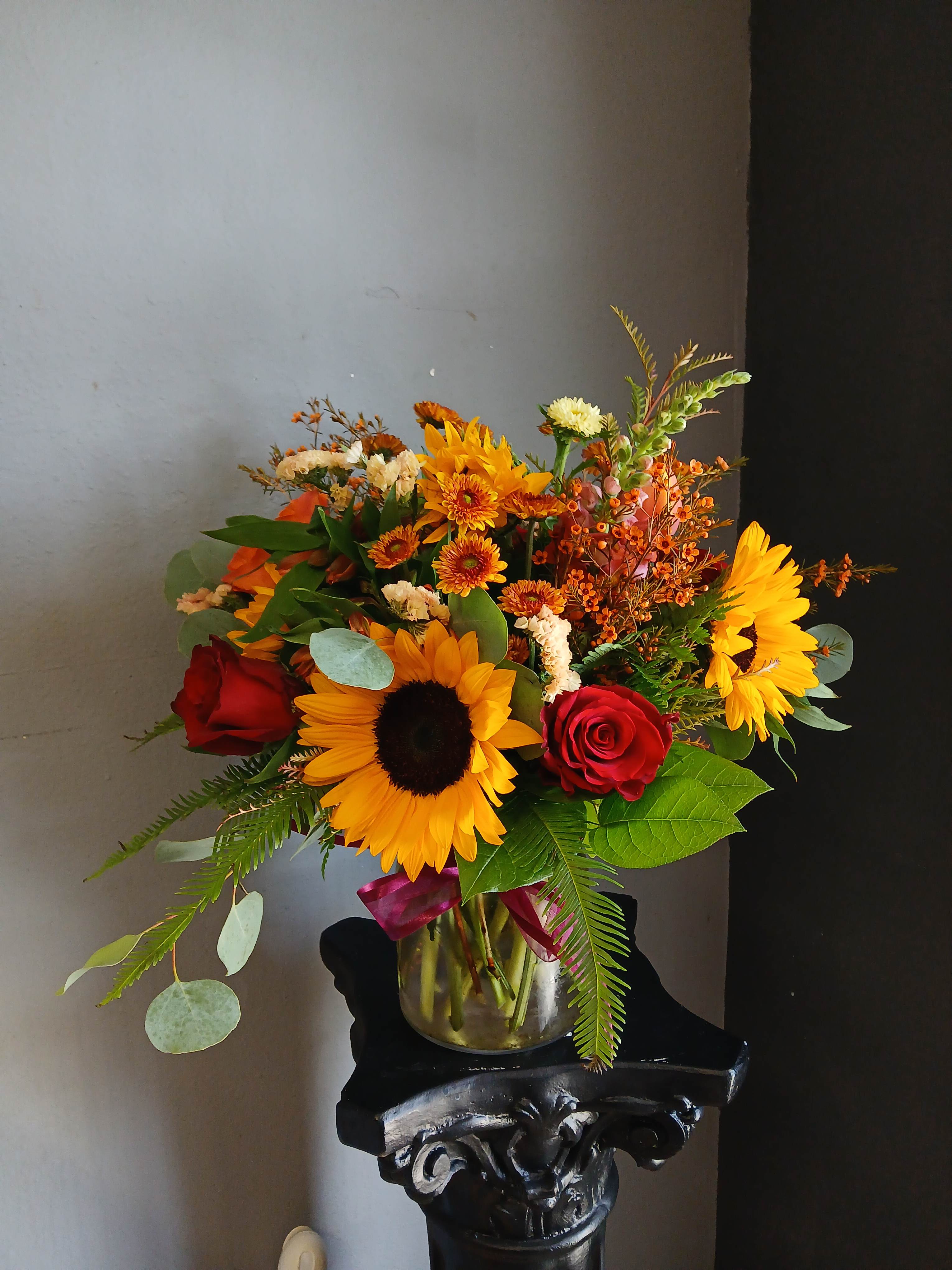 Bouquet of sunflowers and red roses in a glass vase