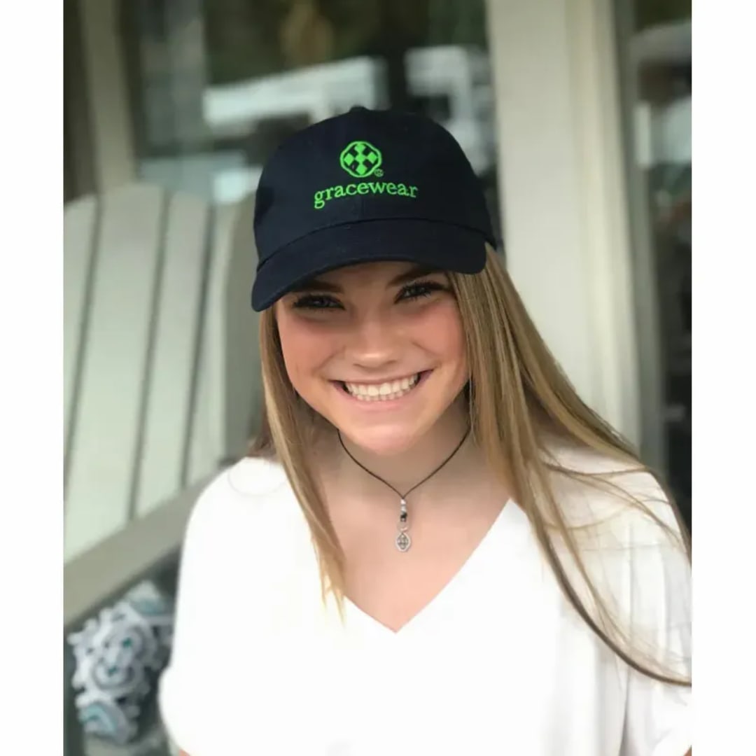 Woman wearing a black cap with green logo and text
