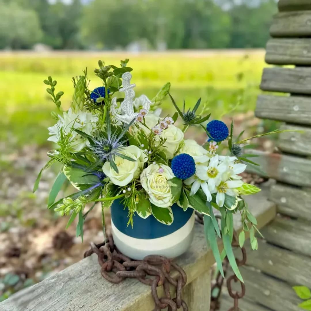 White and blue floral arrangement in a striped ceramic vase