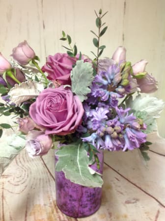 Lavender and pink roses with purple hyacinths in a purple glass vase