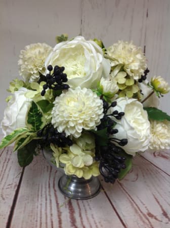 Low arrangement of white roses and mums with dark berries in a silver pedestal bowl