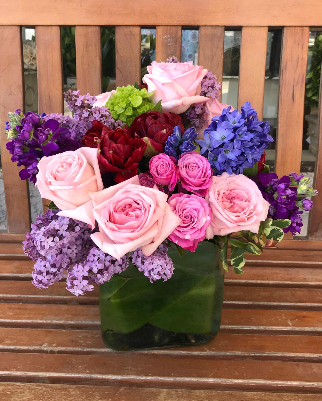 Mixed bouquet of pink, purple, and red flowers in a green vase