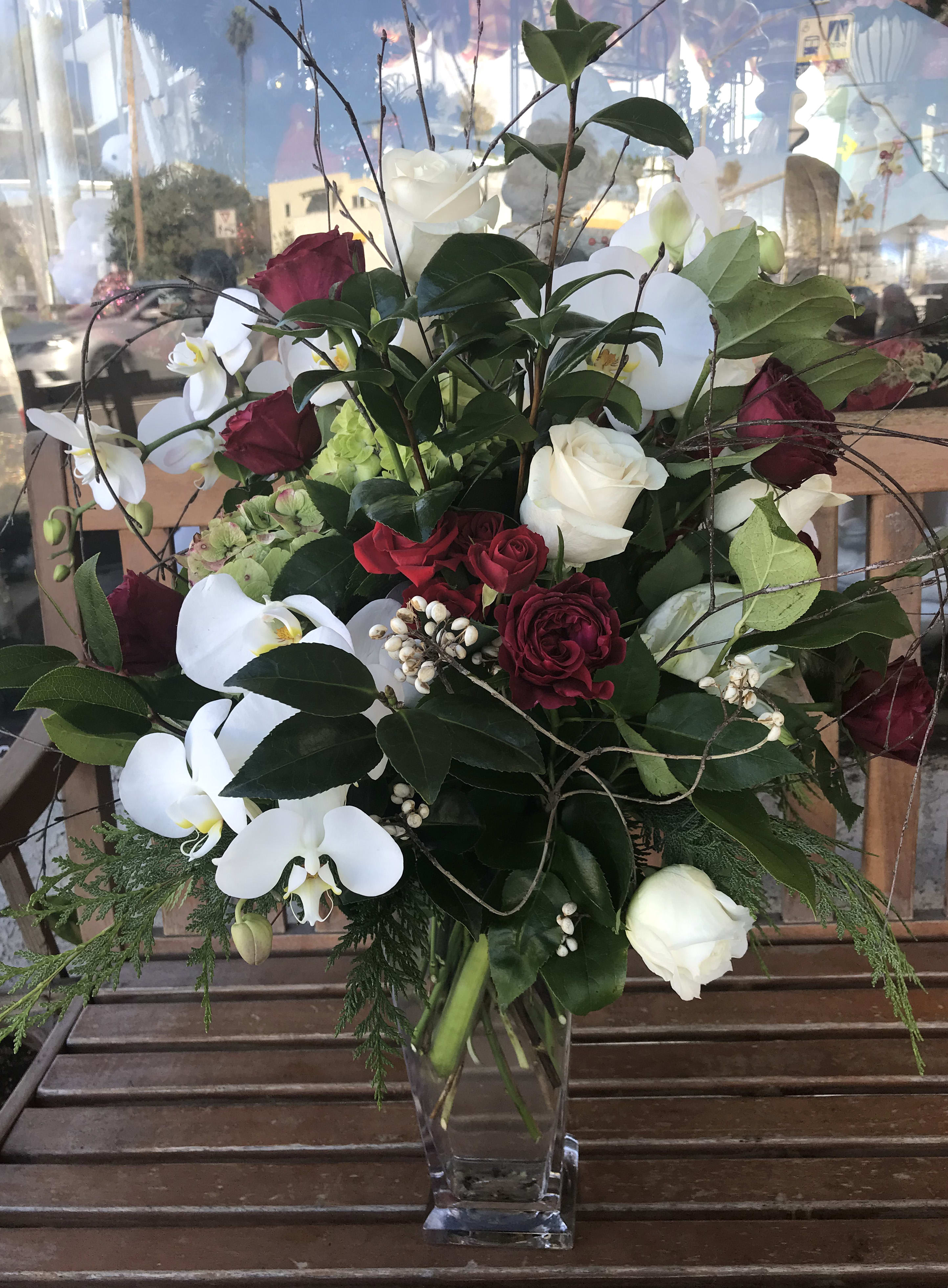 Bouquet of red and white roses with white orchids in a clear glass vase