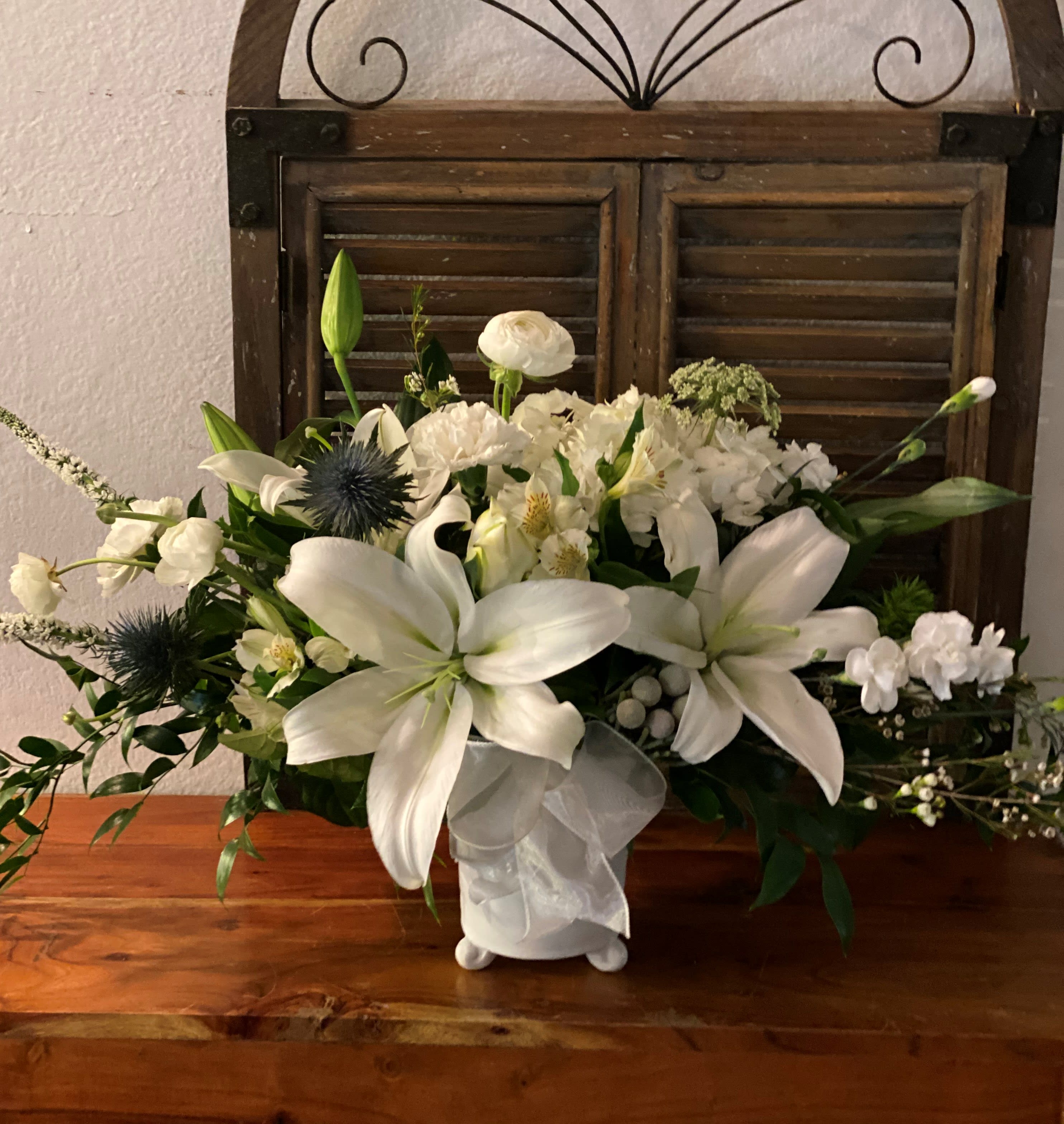 White lily and mixed white floral arrangement in a ceramic vase
