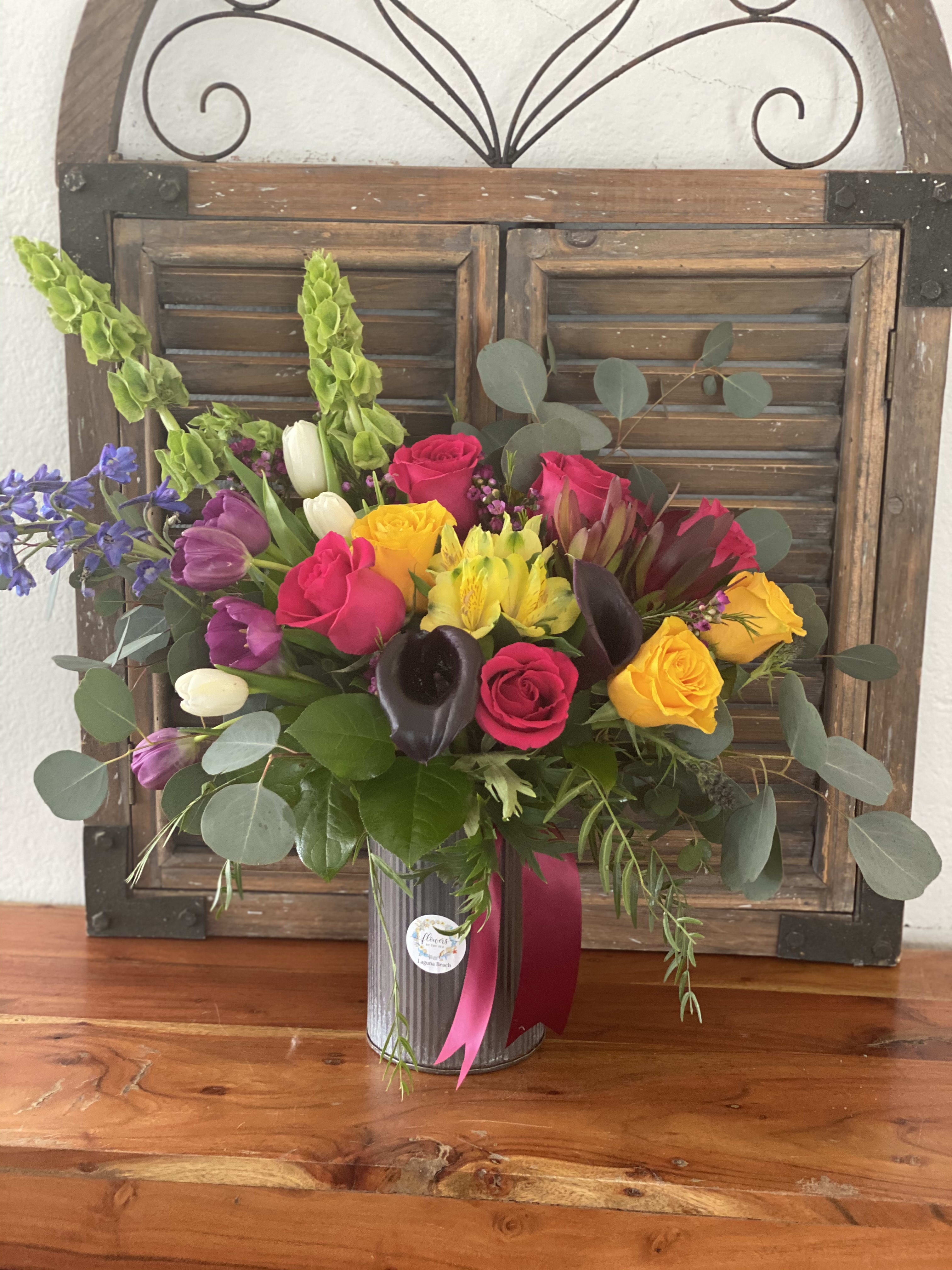 Mixed bouquet of roses, tulips, and calla lilies in a metal vase