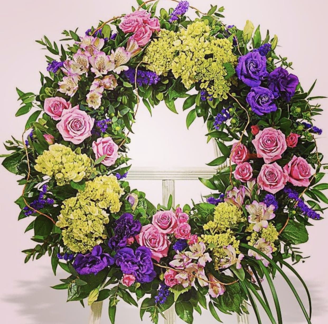 Circular floral wreath with pink roses, purple blooms, and yellow hydrangeas