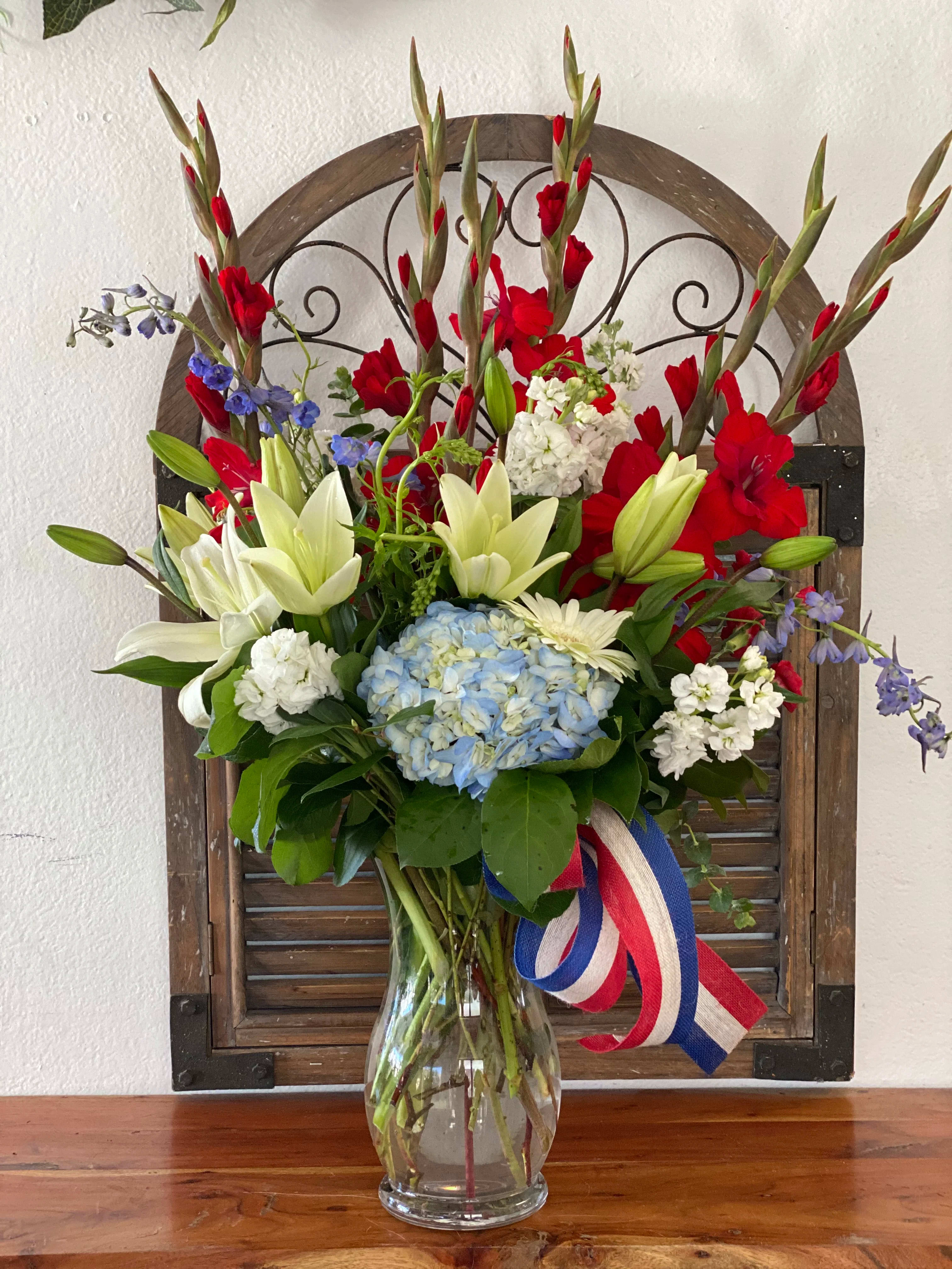 Mixed bouquet with lilies, hydrangea, and red gladiolus in a glass vase