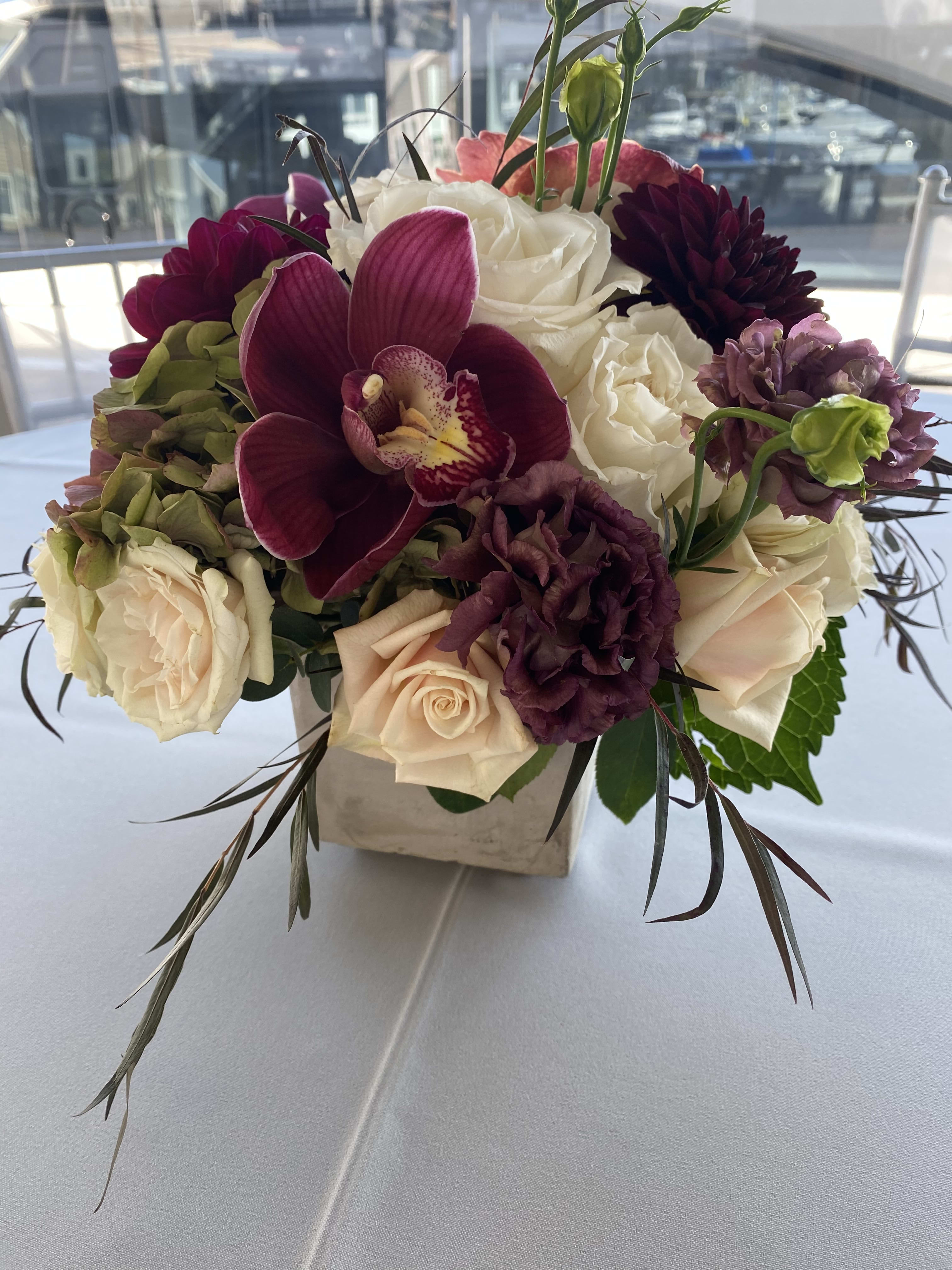 Bouquet of white and burgundy flowers in a square vase