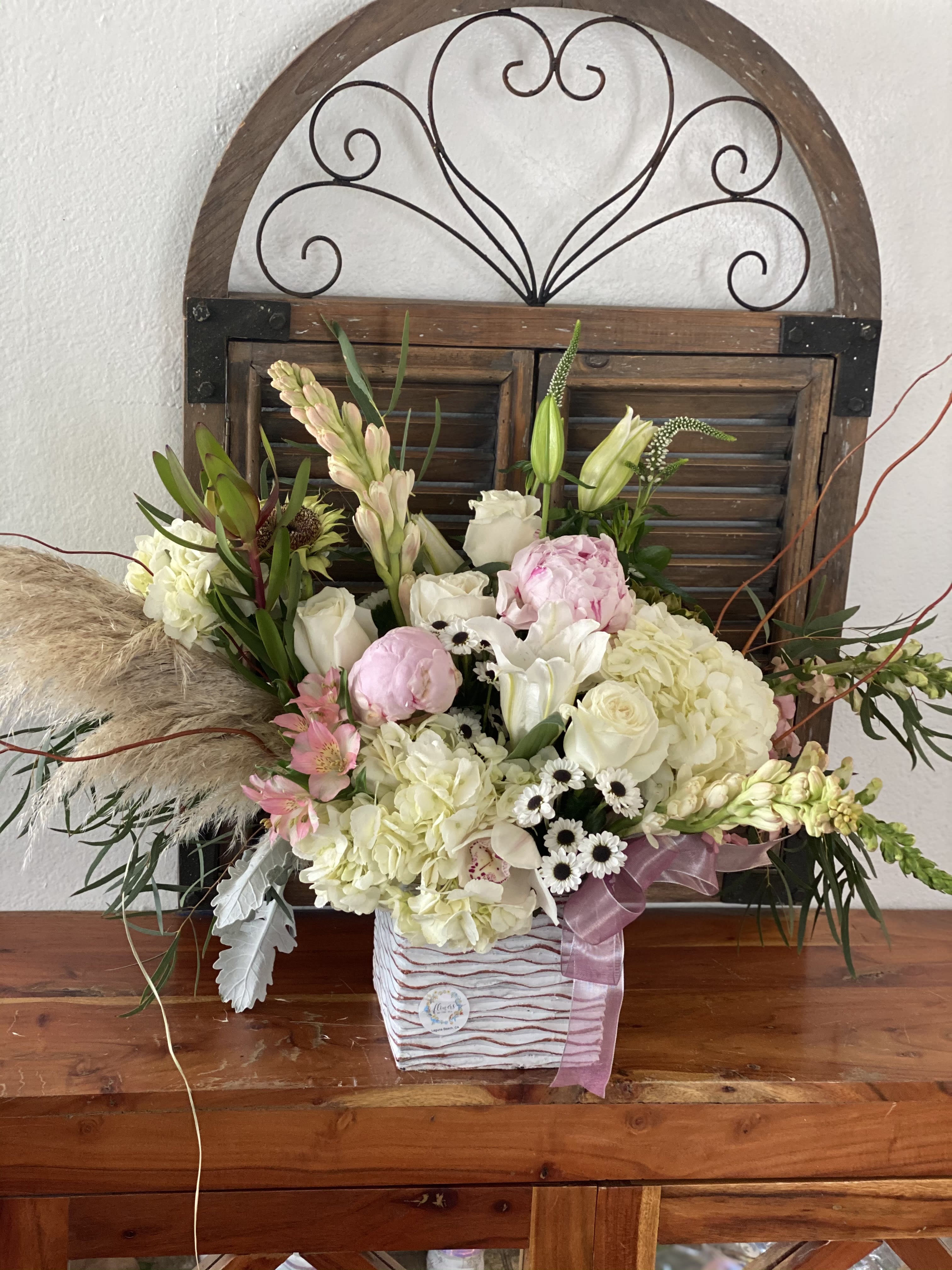 Mixed bouquet in a striped square container with pink ribbon
