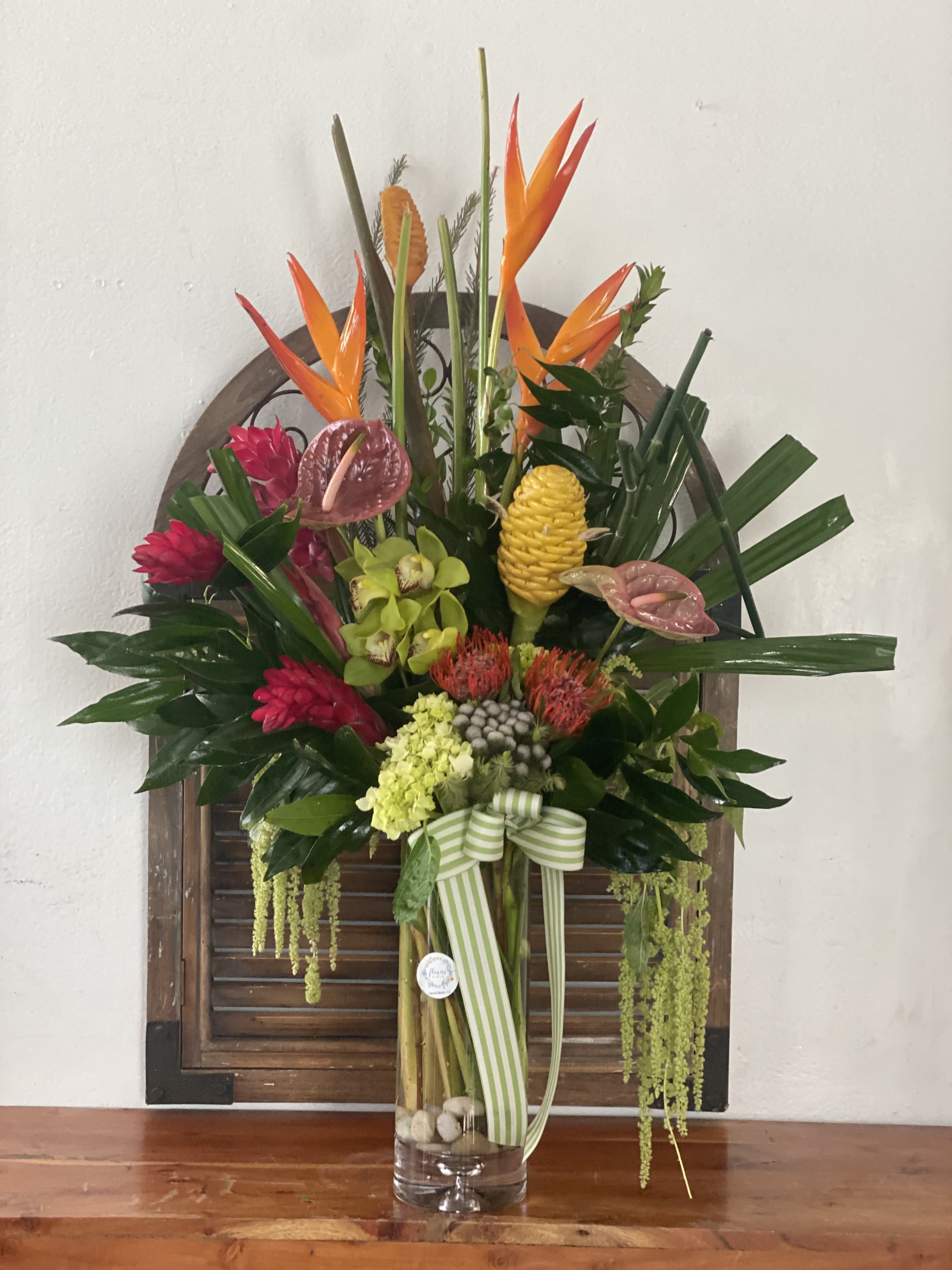 Tropical flower arrangement in a glass vase with orange bird-of-paradise and pink blooms