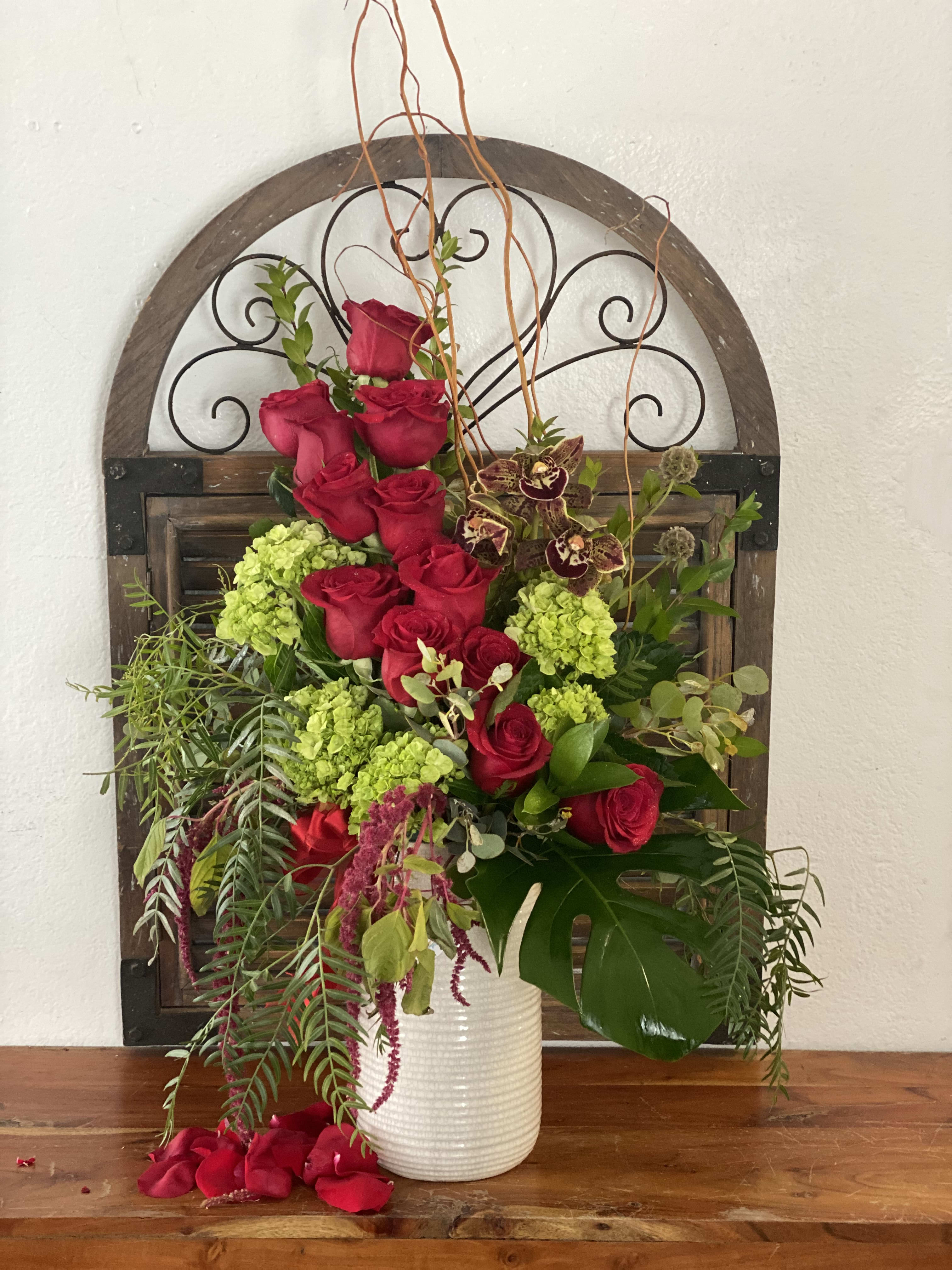 Tall arrangement of red roses and green hydrangeas in a white vase
